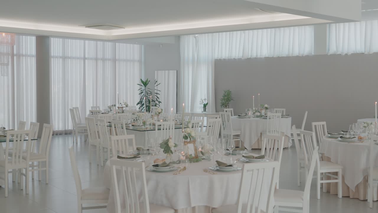 Luminoso salón de bodas con mesas blancas, sillas y velas