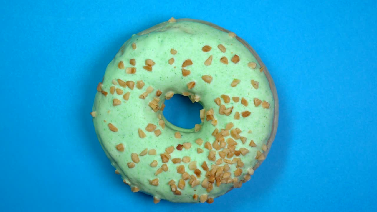 saboroso y fresco rosquilla rosquilla macro disparo de primer plano girando sobre un fondo azul.