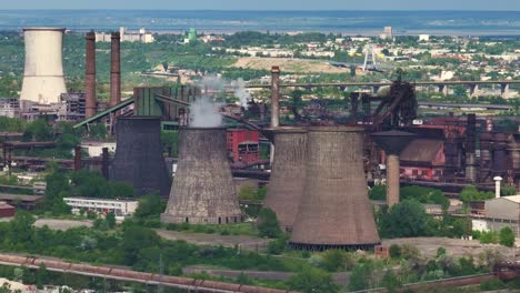 Industrial-smokestacks-set-against-the-skyline-of-a-distant-city-on-a-sunny-clear-day,-close-up-shot