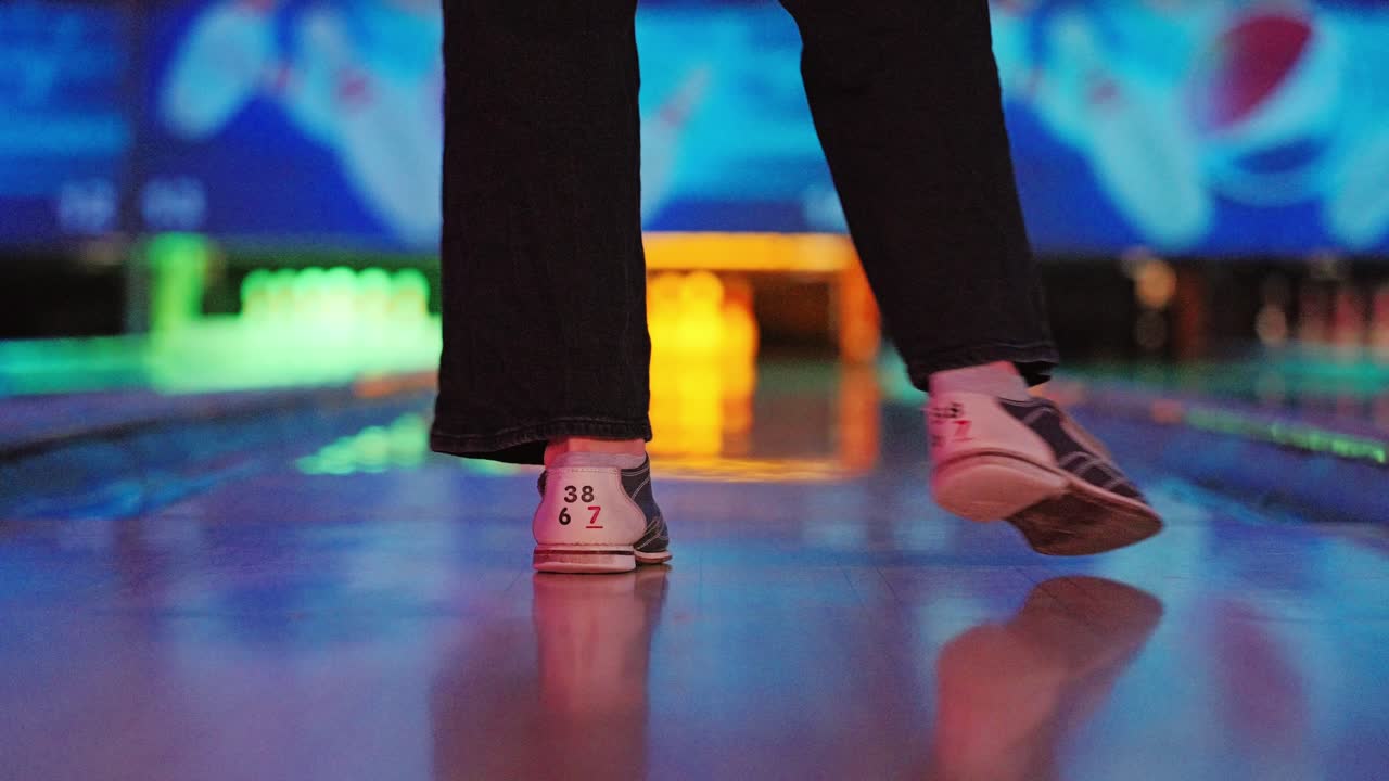 Dynamic colorful motion as woman dances sideways in neon lit bowling alley