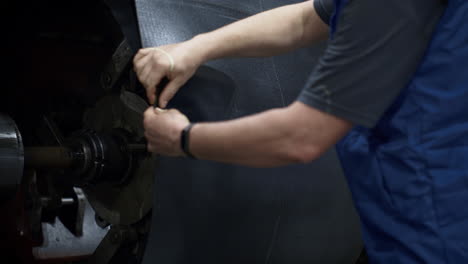 tyre manufacture employee hands operating rubber tape on technological machine