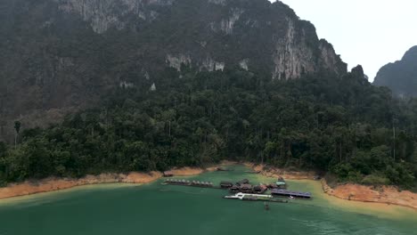 floating village on a serene green lake surrounded by jungle mountains
