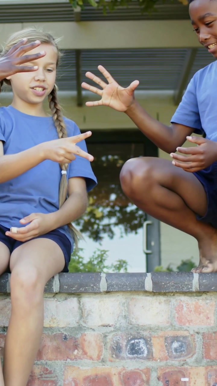 Girl on wall making palm motions, hands responding, boy joining, trading moves for education