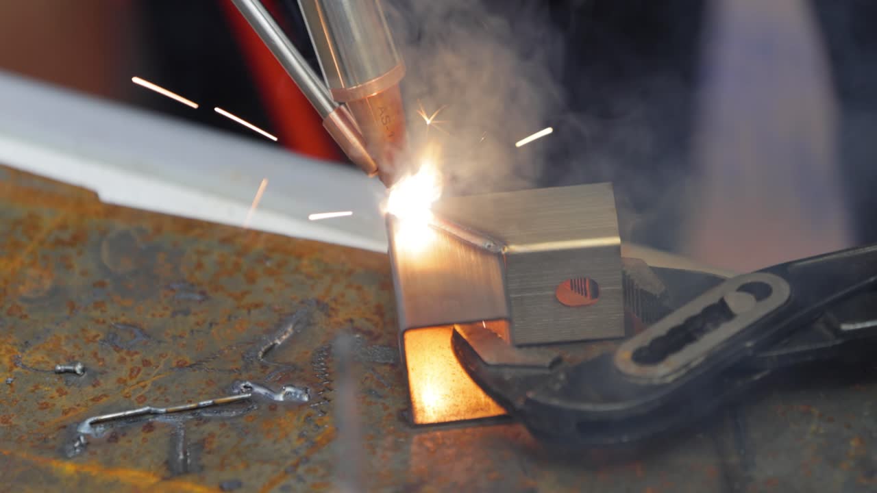 Laser welding machine with hand hold gun. Laser welding is shown in close-up.