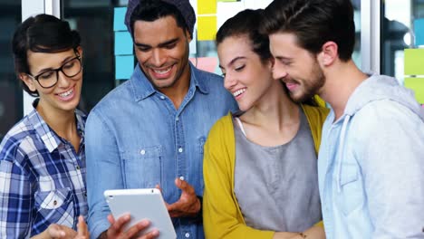 Smiling-executives-discussing-over-digital-tablet-during-meeting