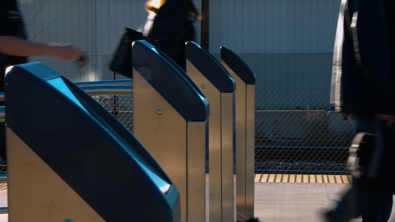 People scanning their badges for a commuter train.  Finishing a days work.  Walking to the station and waiting for the train to arrive.