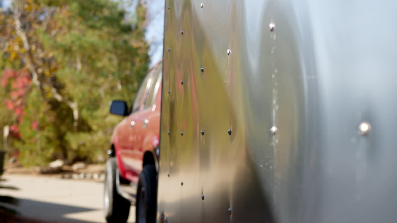 캠프장에서 전기 연결 플러그가 있는 금속 눈물방울 여행 트레일러의 측면을 따라 수직 슬라이드 샷