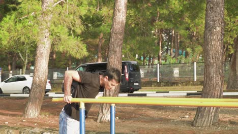 hombre haciendo inmersiones en barras paralelas en un parque