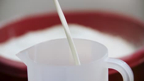 pouring milk into a measuring cup for baking