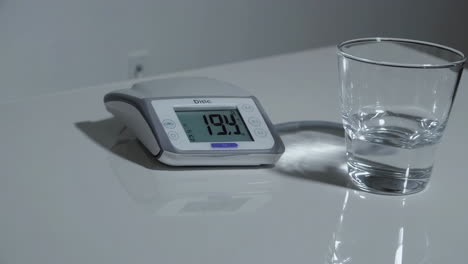 blood pressure monitor and glass of water on table