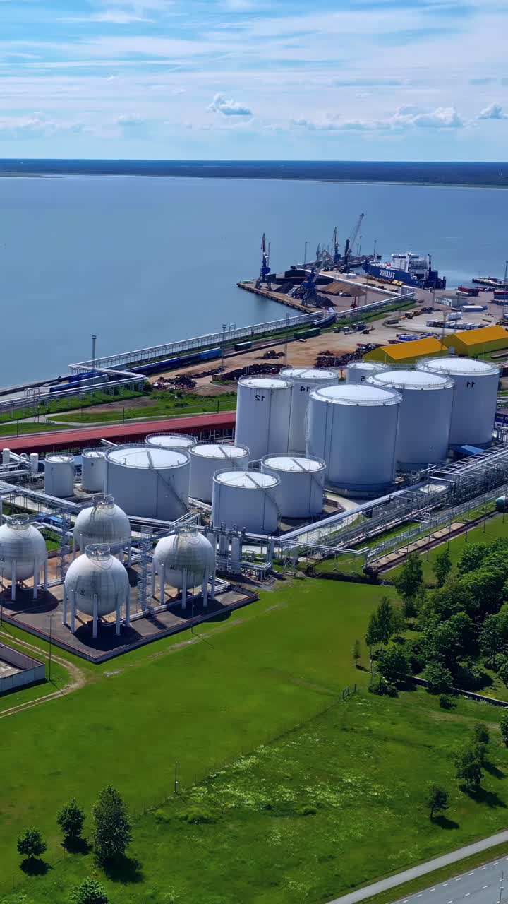 Aerial view of Ventspils port terminal in Latvia with oil and gas storage tanks, pipelines, and shipping docks by the Baltic Sea