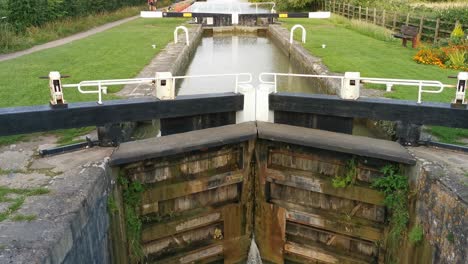 a slow rising reveal shot of a very large and old wooden locks on a very cloudy and overcast day in a famous lock in england called the kennet and avon canal