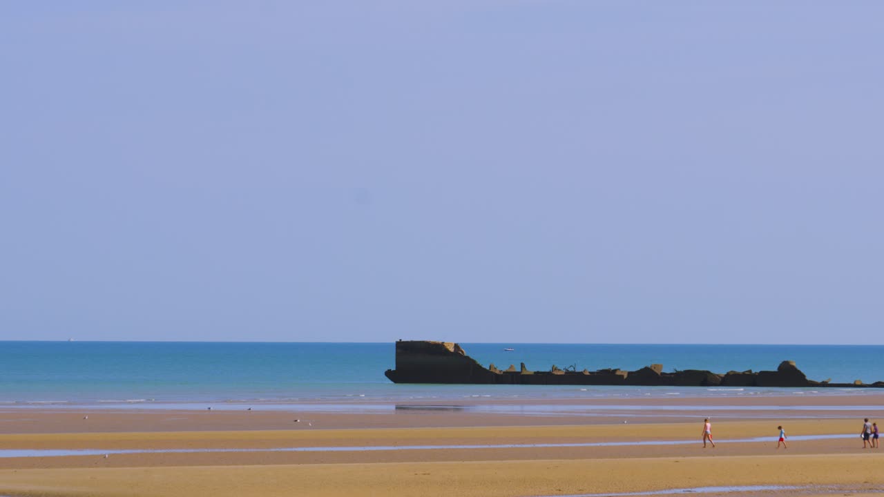 WW2 Artificial Harbour Remnant on Gold Beach in Normandy, France with People in Bay on Holiday Enjoying Summer Vacation 4K