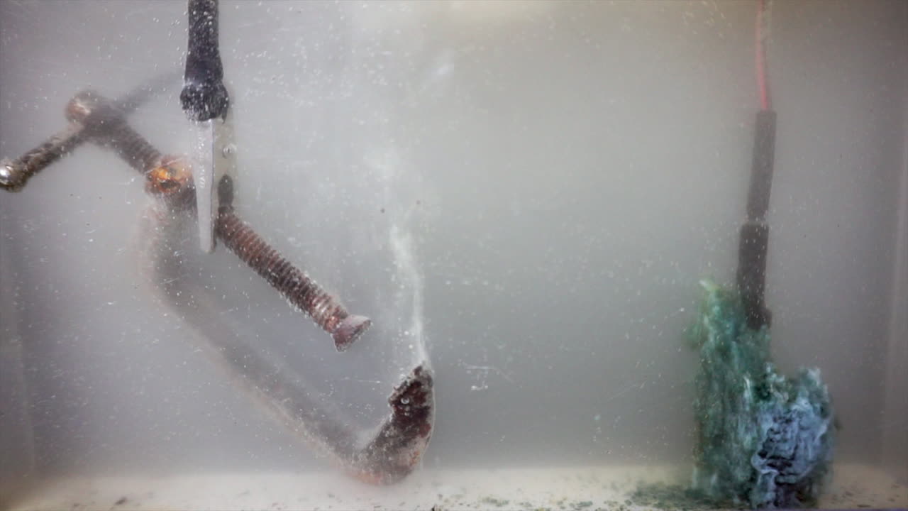 Electric current flows removing rust from a c-clamp (left) and depositing minerals on the anode (right)