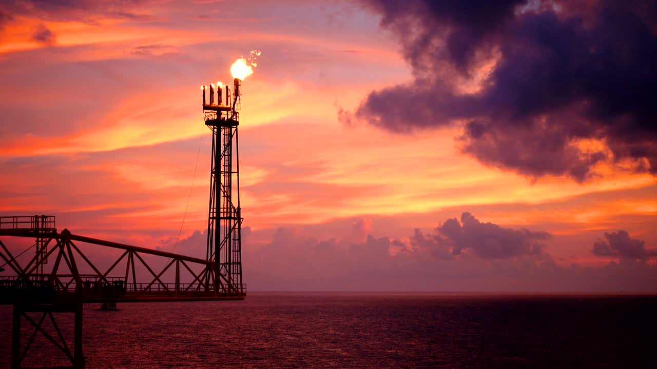 석유 및 가스 산업 개념을 위해 태양이 뜨고 아침에 아름다운 구름과 함께 불꽃이 타는 다리를 가진 석유와 가스 플랫폼의 영상.