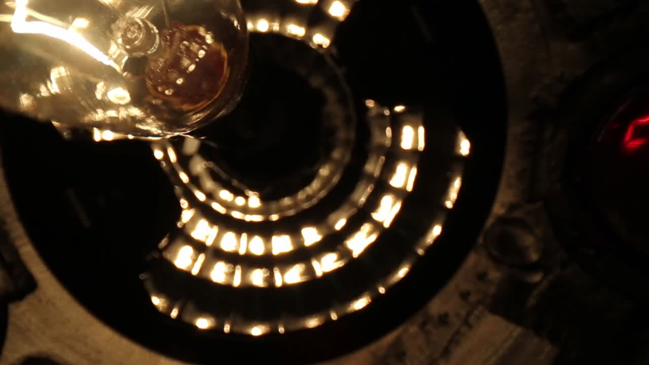 디스코 볼 내부를 비추는 하나의 랜턴 스타일 전구, 전구 외부의 훌륭한 세부 사항 및 전구 내부의 조명 필라멘트에 대한 좋은 세부 사항을 천천히 지나갑니다.