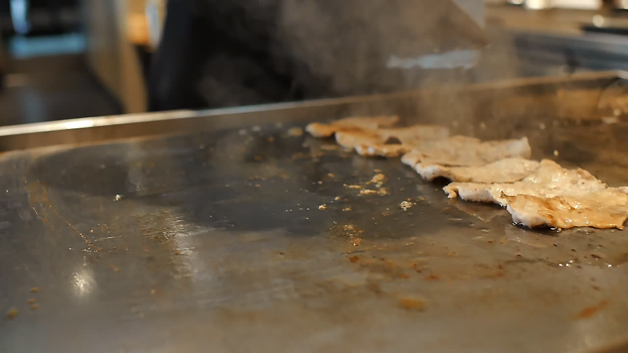 Close-up of a skilled chef preparing teppanyaki Japanese cuisine on a hot iron griddle in front of guests, grilling fresh ingredients with flair. Perfect for Japanese food culture and live cooking