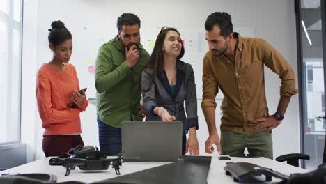 Diverse-group-of-work-colleagues-looking-at-laptop-and-discussing-in-meeting-room