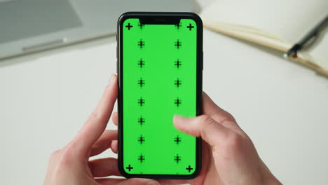 person holding smartphone with green screen