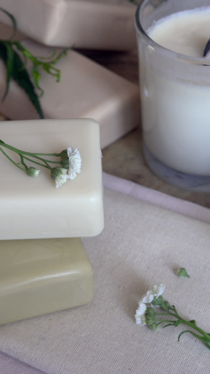 Close up of white candles and soaps on a wooden surface. Vertical