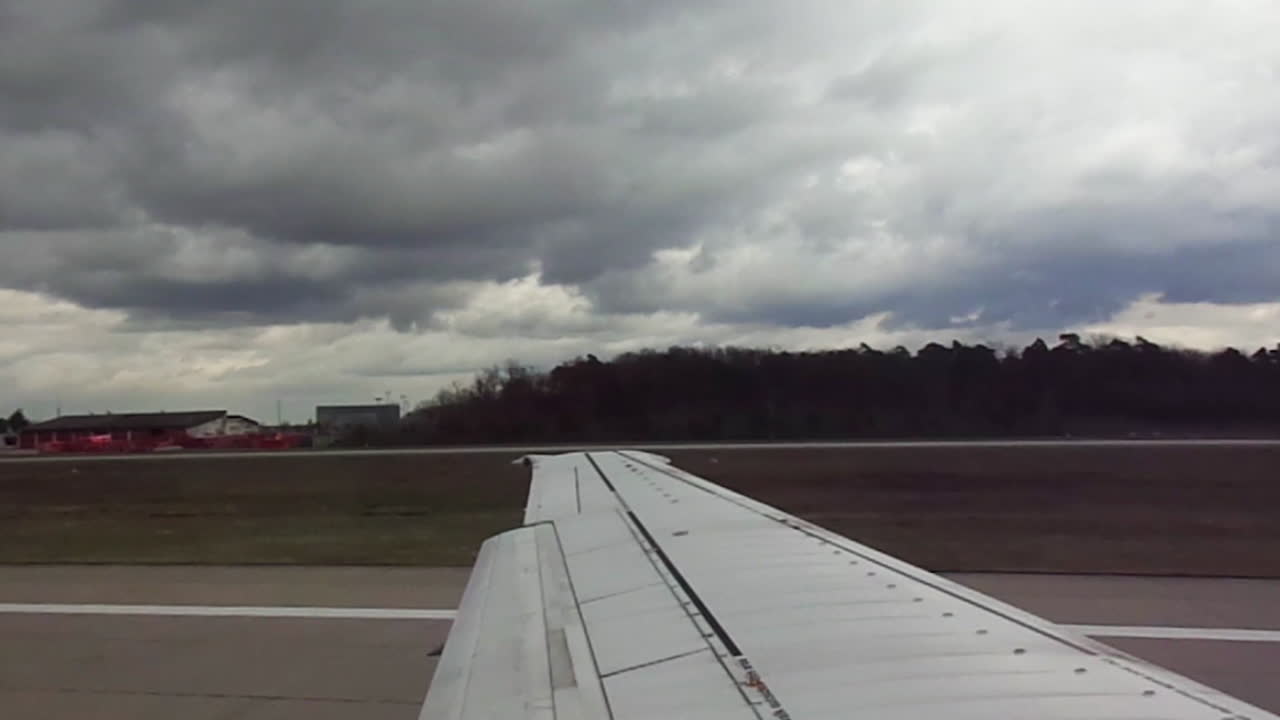 Airplane wing view as flight takes off from a runway under cloudy skies in Bangalore, India