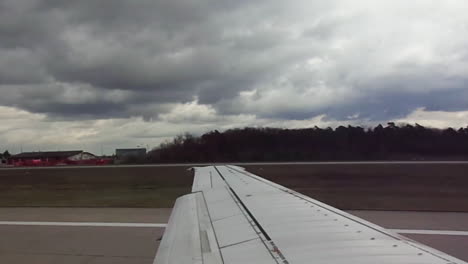 airplane wing view as flight takes off from a runway under cloudy skies in bangalore, india