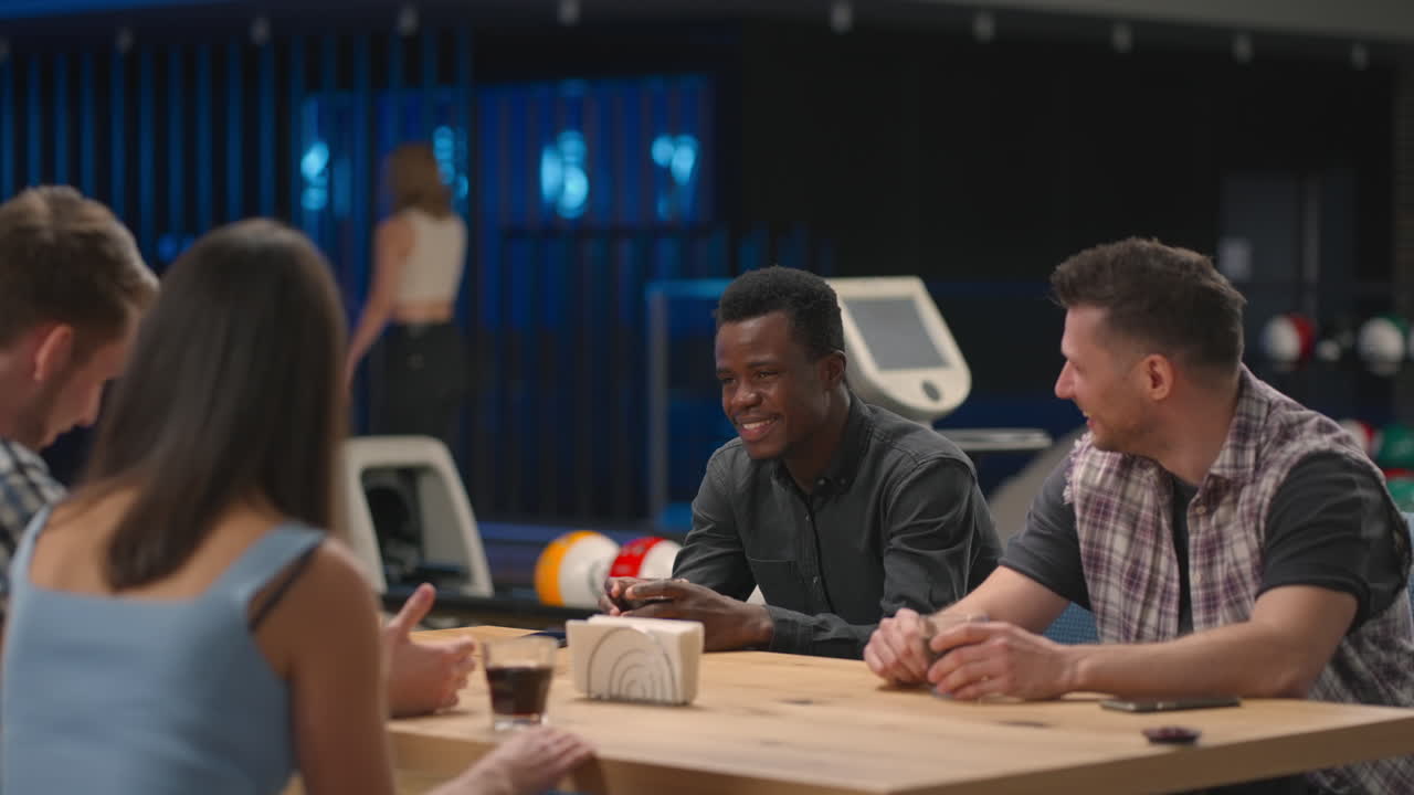 una mujer golpea una huelga en una pista de bolos y corre a sus amigos para regocijarse juntos y dar un alto cinco. celebrar la victoria juntos con amigos