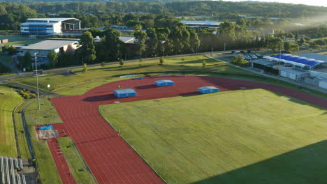 fast man running laps in athletics sport field, aerial 4k drone