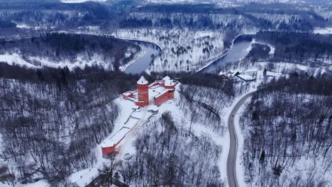 turaida castle, winter landscape, snowy trees and the winding gauja river, drone