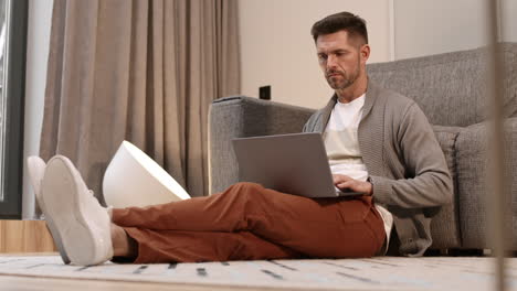 man using computer leaning on couch