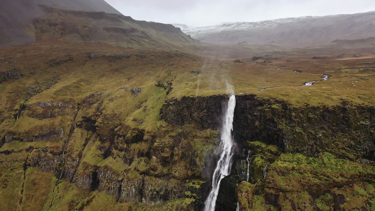 vuelo de drones hacia una cascada arrastrada por el viento en islandia