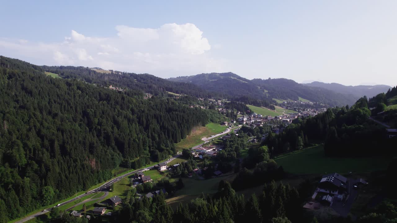 Aerial view of holiday winter sports region during summer with chalets in lush greenery against the mountain side
