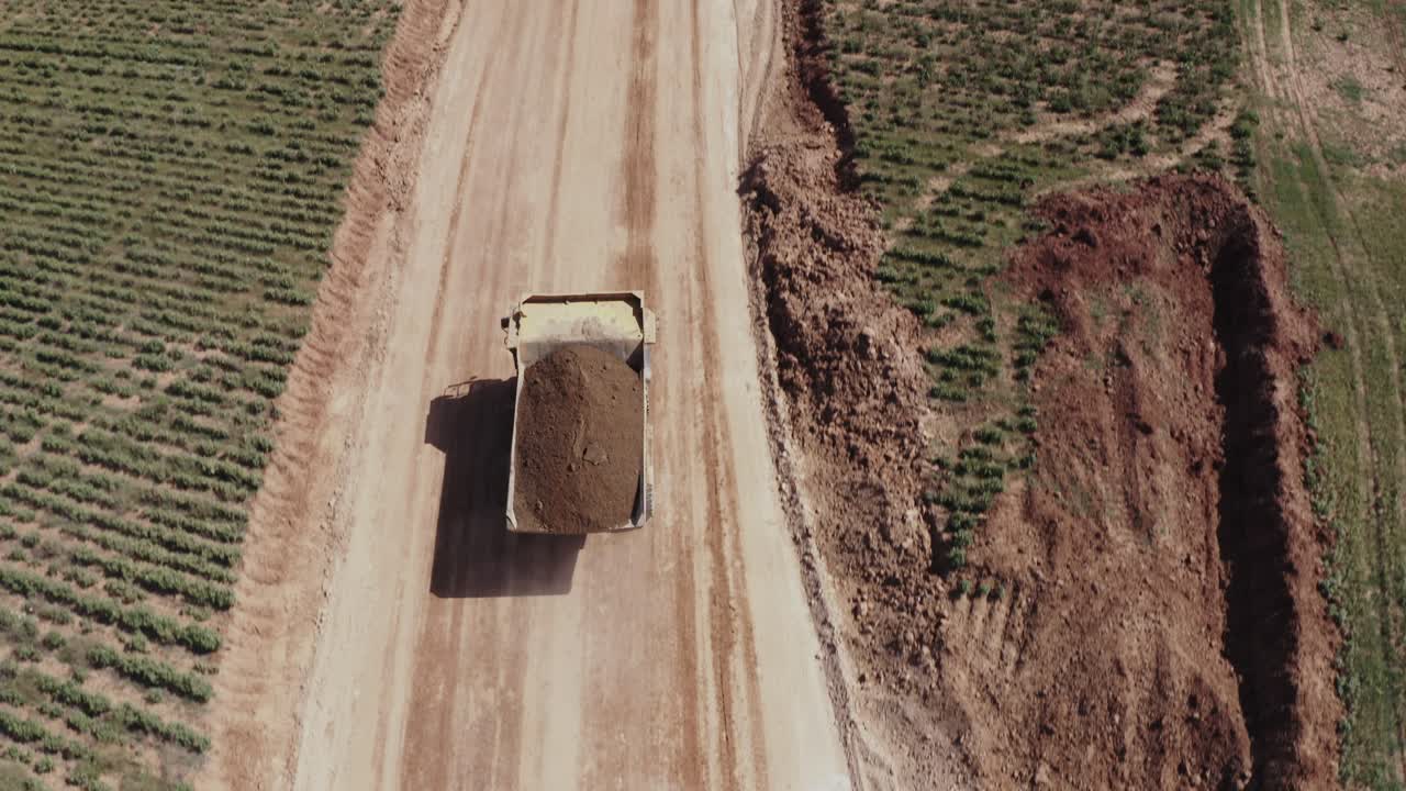A large truck loaded with sand is heading towards the construction site, aerial shots of the truck alongside the construction site and materials