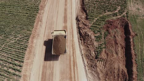 un gran camión cargado de arena se dirige hacia el sitio de construcción, fotos aéreas del camión junto con el sitio de construcción y los materiales