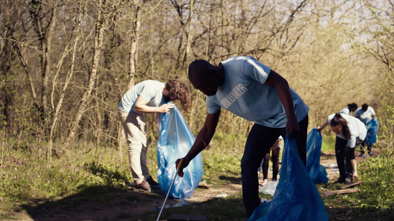 African american man volunteer collecting trash and plastic waste with tongs
