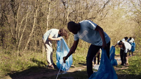 african american man volunteer collecting trash and plastic waste with tongs