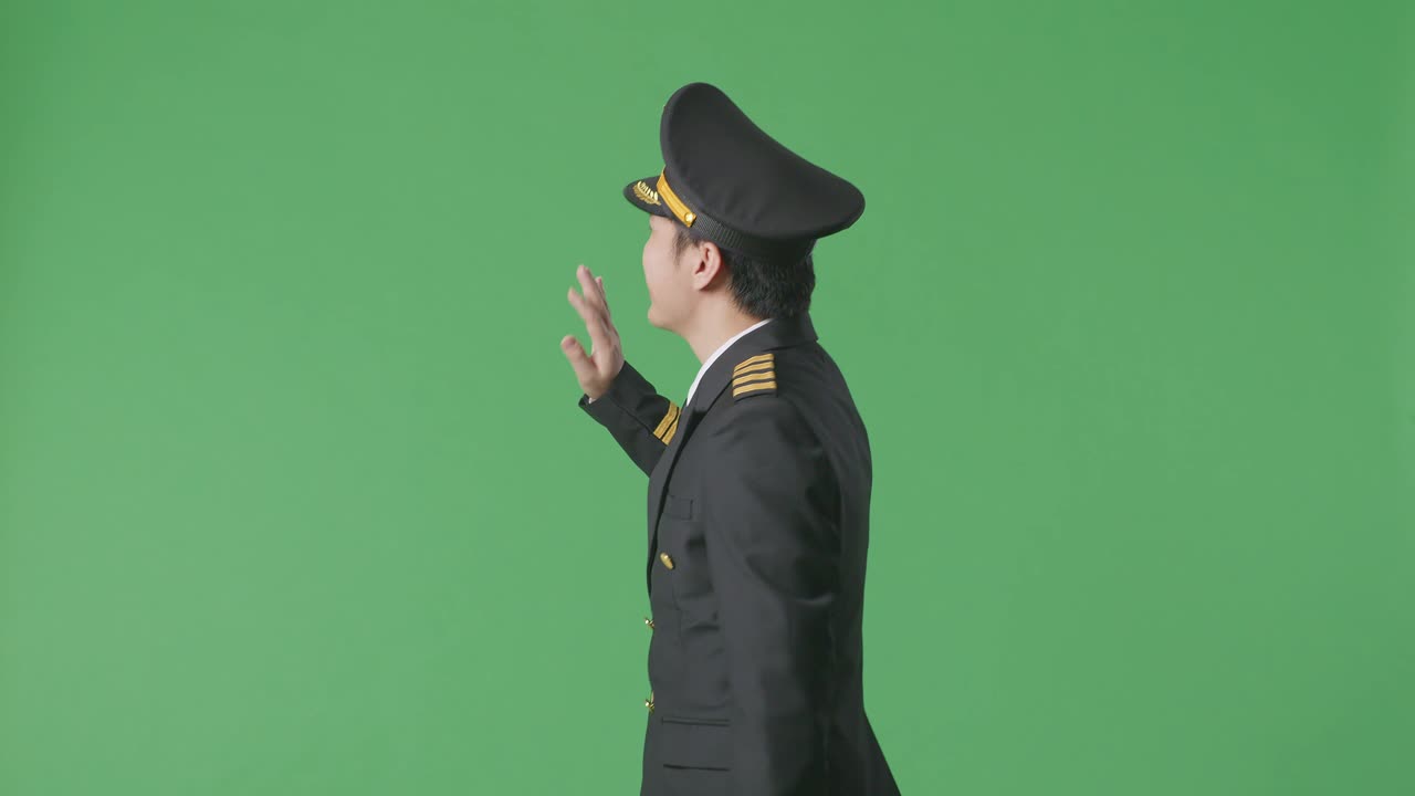 Side View Of Asian Man Pilot Walking And Waving Hand In The Green Screen Background Studio