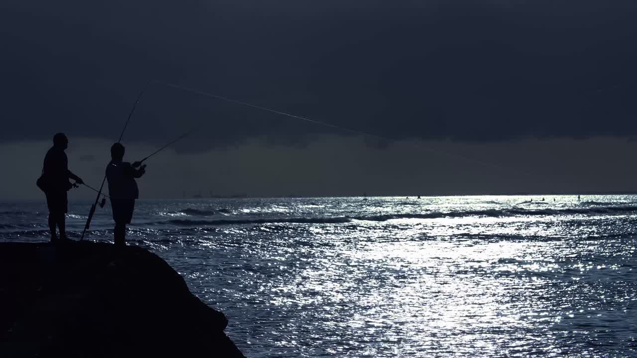 호놀룰루 하와이의 알라모아나 해변 공원에서 시원한 푸른 석양을 바라보는 어부들