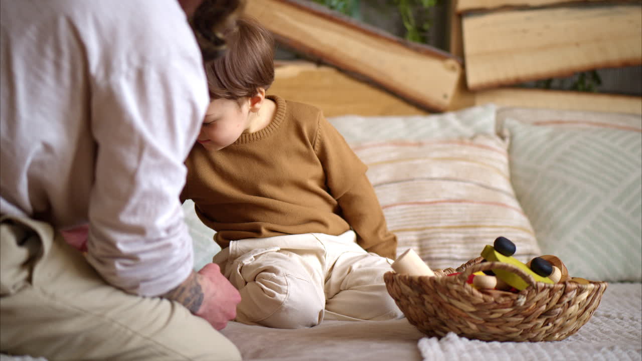Father playing with his son with colourful, ecological wooden toys on the bed