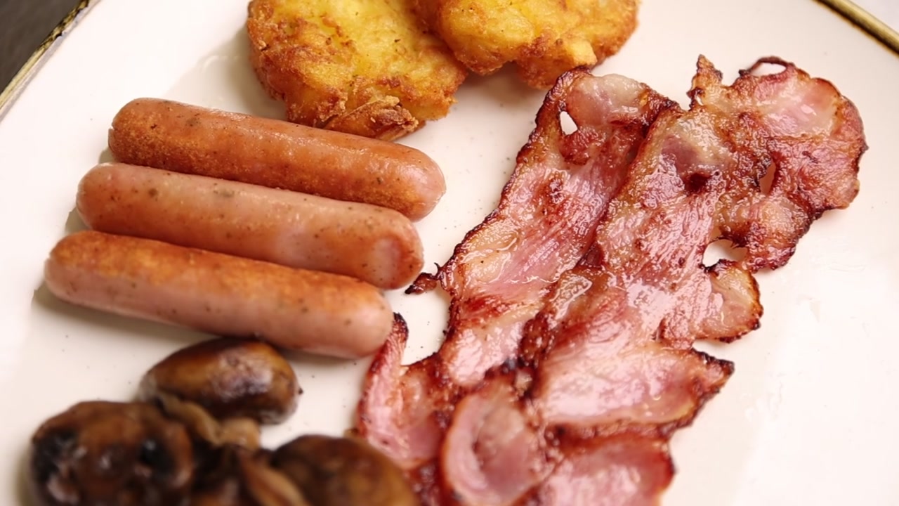 Delizioso piatto da colazione con pancetta croccante, salsicce e hash brown