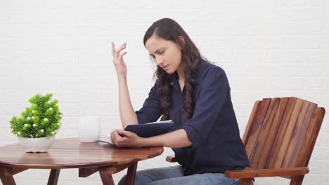 shocked indian girl reading a book at a cafe