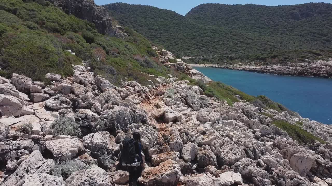 Veduta aerea di un escursionista a lunga distanza che cammina lungo un sentiero roccioso lungo la costa nella Turchia meridionale sulla Via Licia in primavera