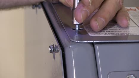 tightening screws on exterior metal plating of paint mixer machine with a socket power drill close up