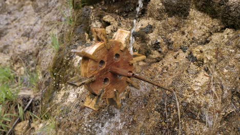 small wooden water mill spinning under dripping water