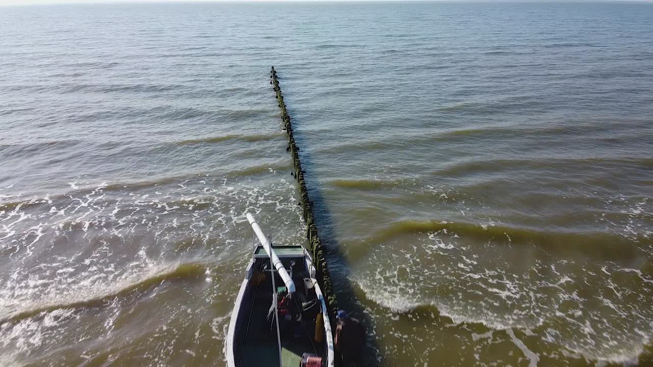 hermosa vista aérea de pájaro del barco de pesca de pescadores costeros verdes atracado en el viejo muelle de madera en un día soleado, barco de cheques de pescadores, orilla del mar tranquila, disparo de drones de gran angular avanzando