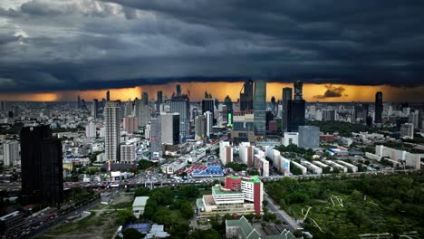 dramatic storm clouds gather over bangkok city skyline at sunset. aerial view