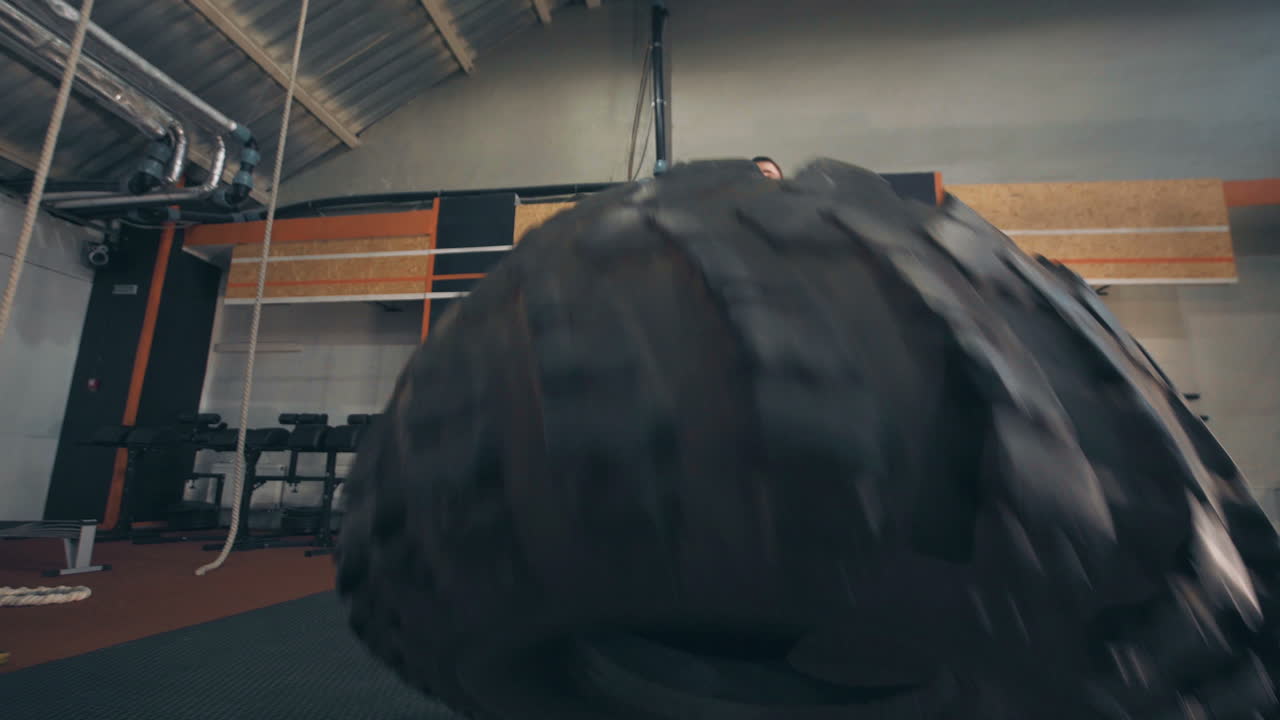 Man Lifting a Tire in a Gym