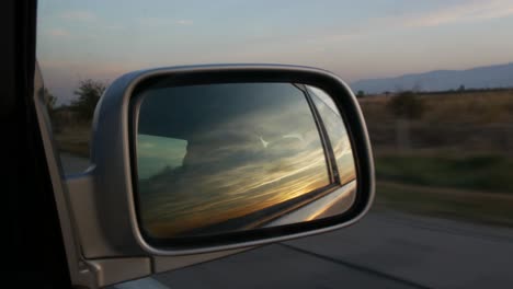 sunset reflected in the right side mirror of a car