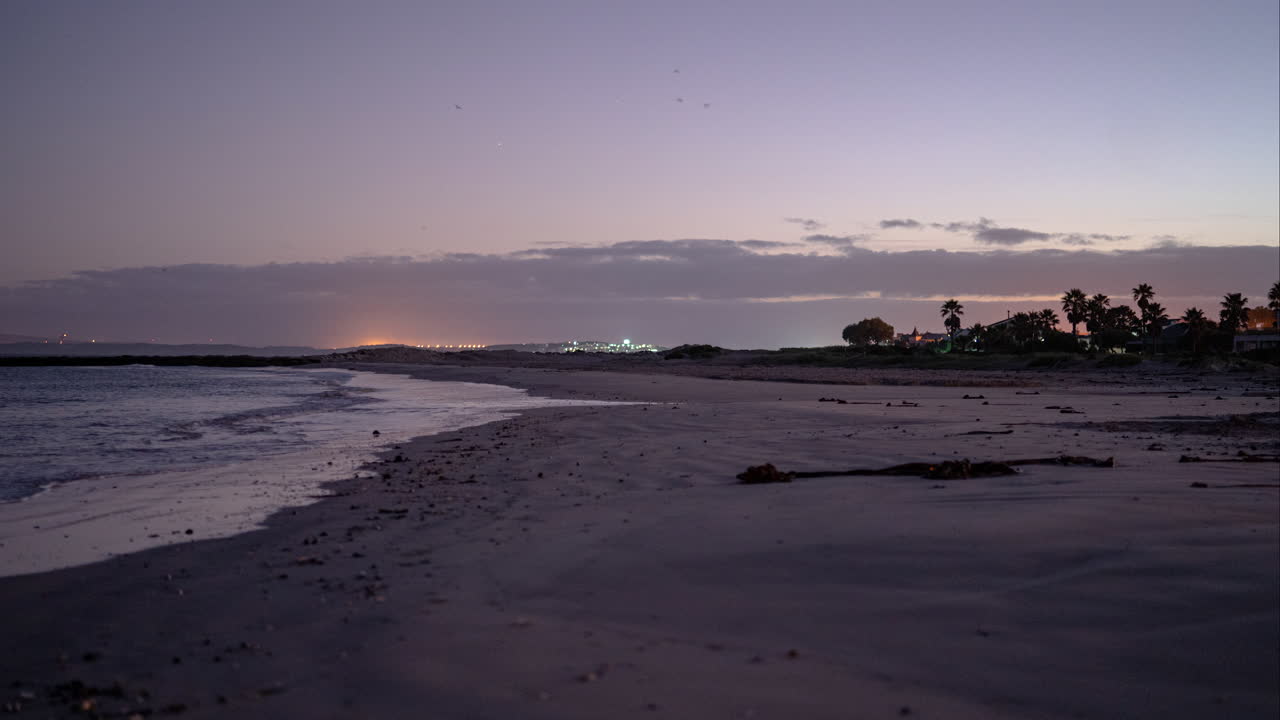 timelapse del amanecer en la playa con ciudad costera al fondo
