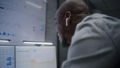 financial analyst suffering from financial crisis, yelling during call, analyzing exchange market charts in office. african american businessman furious about stock market collapse. vertical shot.